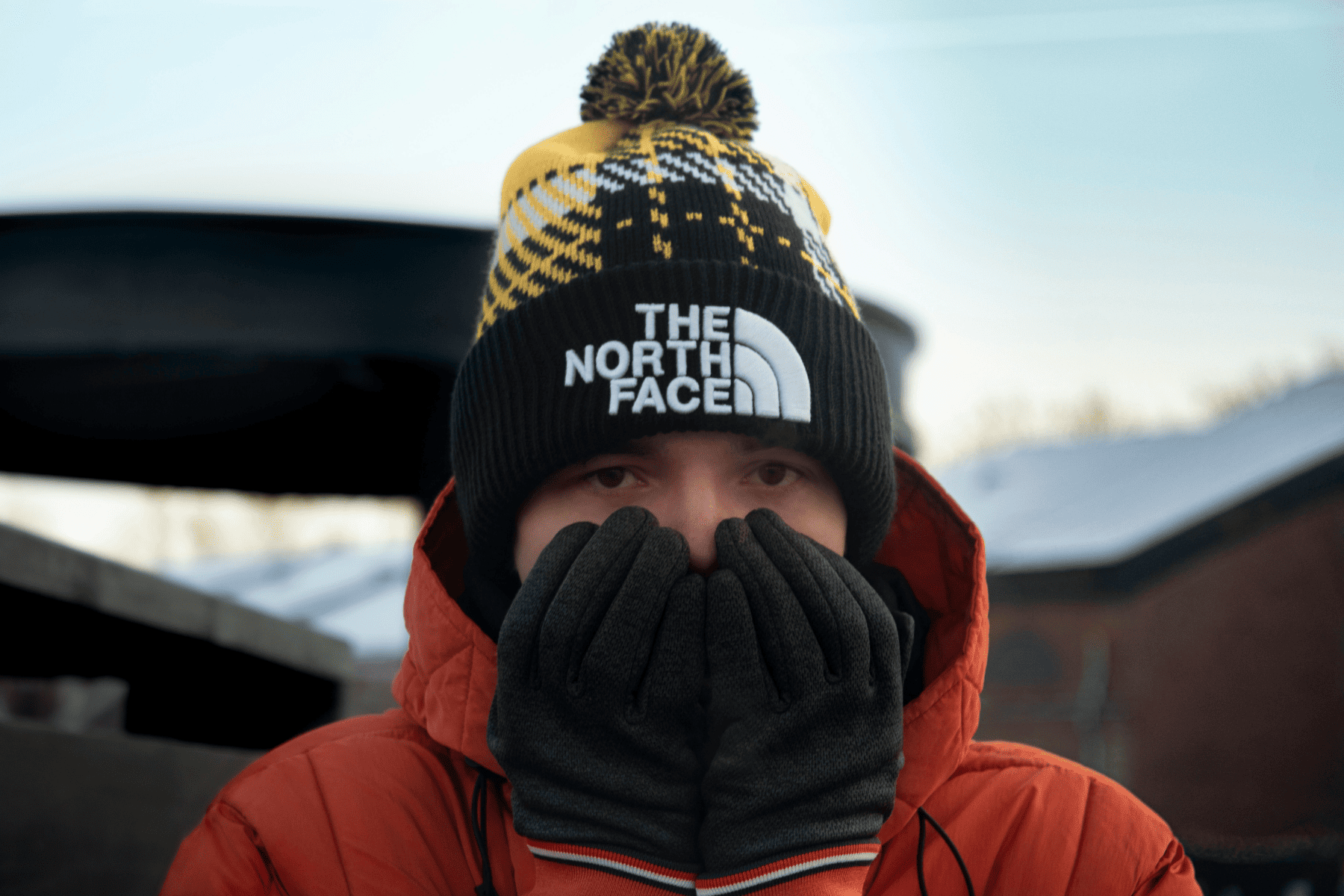 גבר לובש מעיל נורת' פייס, כובע של הממותג דה נורת' פייס וכפפות -  The North Face. ברקע שלג