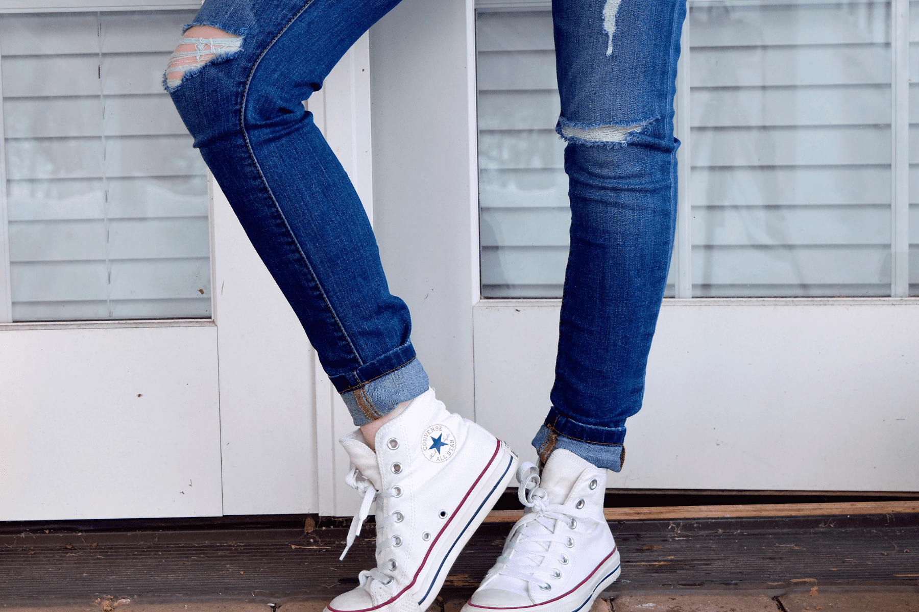 אישה נועלת נעלי סניקרס קונברס אולסטאר (Allstar Converse) לבנות
